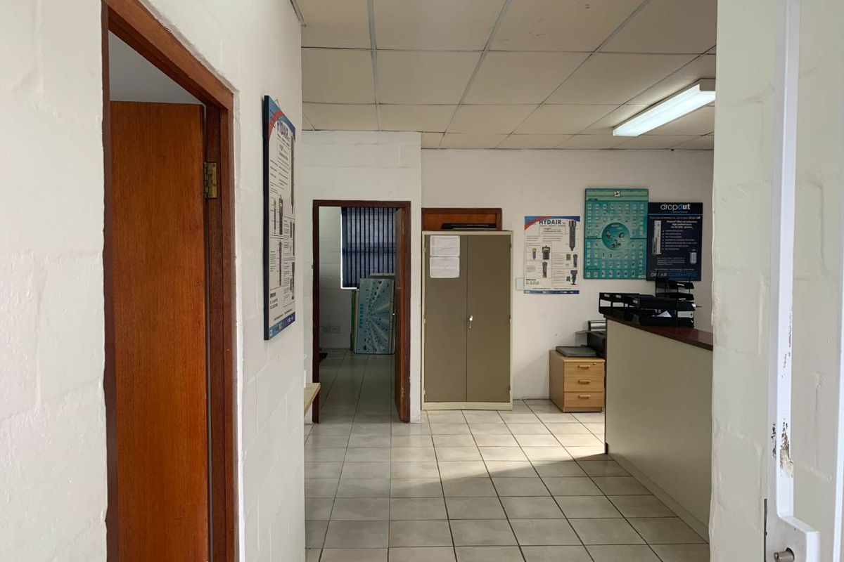 A functional office space featuring tiled flooring, a suspended ceiling, and a built-in reception counter, suitable for commercial or administrative use.
