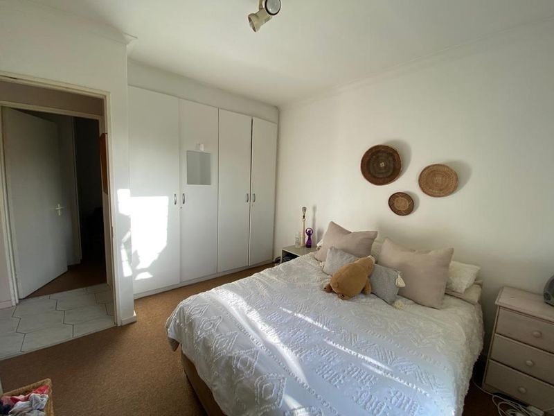 A bedroom featuring built-in cupboards, neutral wall finishes, and carpeted flooring, offering a functional and well-lit living space.
