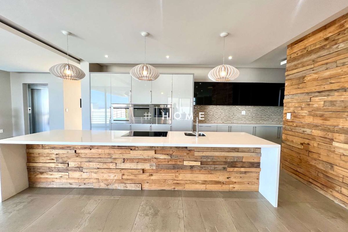 Modern kitchen featuring a large central island with a stone countertop, integrated appliances, and decorative timber cladding on the island and feature wall.