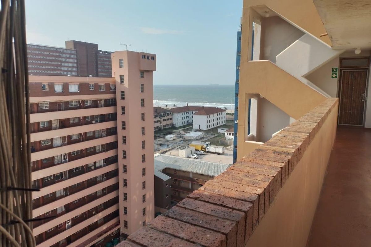 An elevated view from an apartment walkway overlooking the surrounding urban neighborhood and the distant coastline.