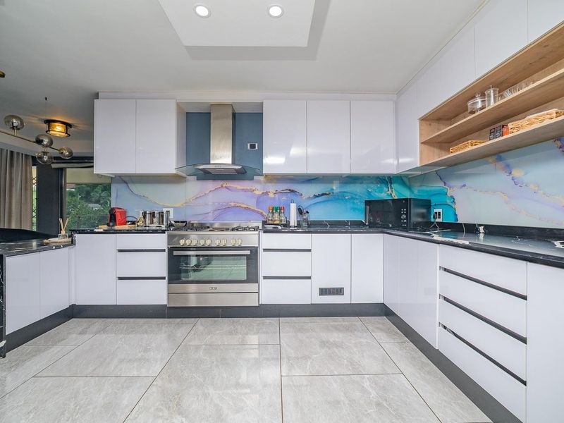 Modern kitchen featuring high-gloss white cabinetry, stone countertops, a striking decorative glass splashback, and integrated stainless steel appliances.