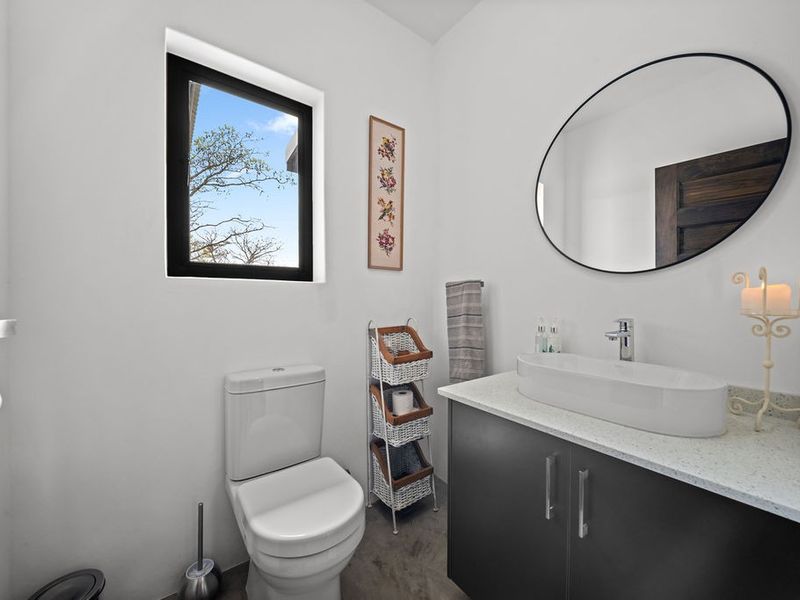 A modern bathroom featuring a sleek vanity with a vessel sink, stone countertop, and a contemporary toilet under a window.