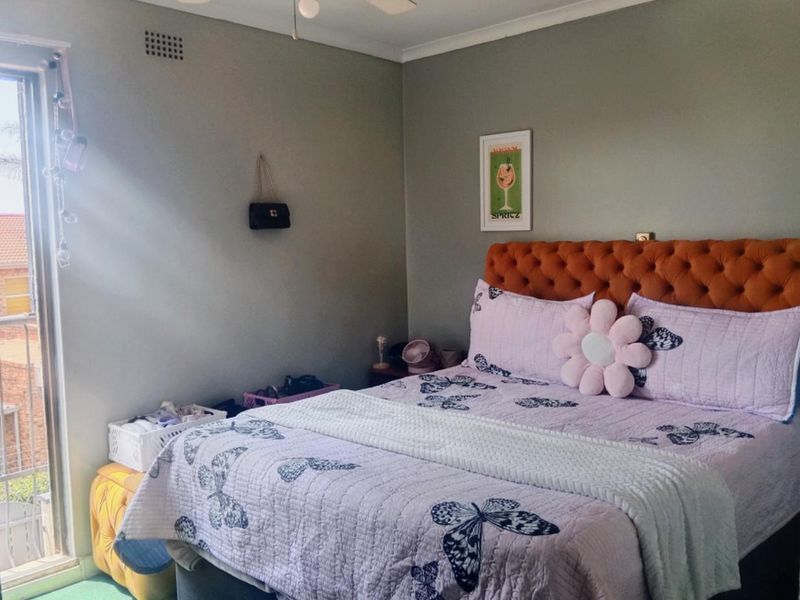 A bedroom featuring a ceiling fan, ventilation grille, and a sliding glass door providing access to an outdoor area.