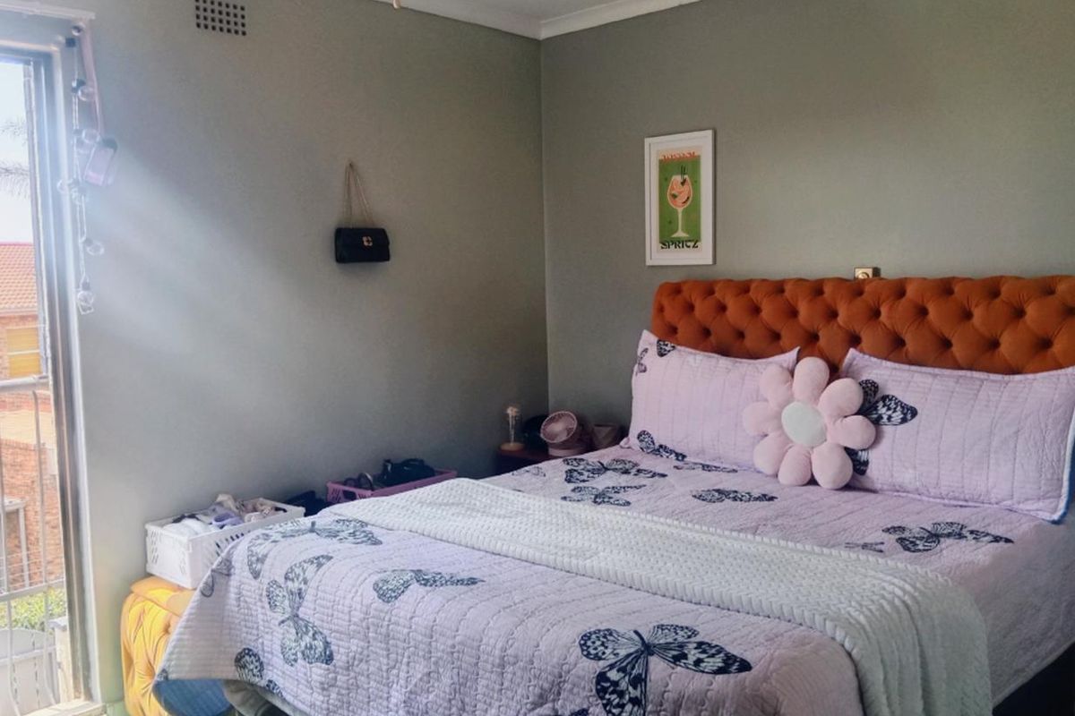 A bedroom featuring a ceiling fan, ventilation grille, and a sliding glass door providing access to an outdoor area.