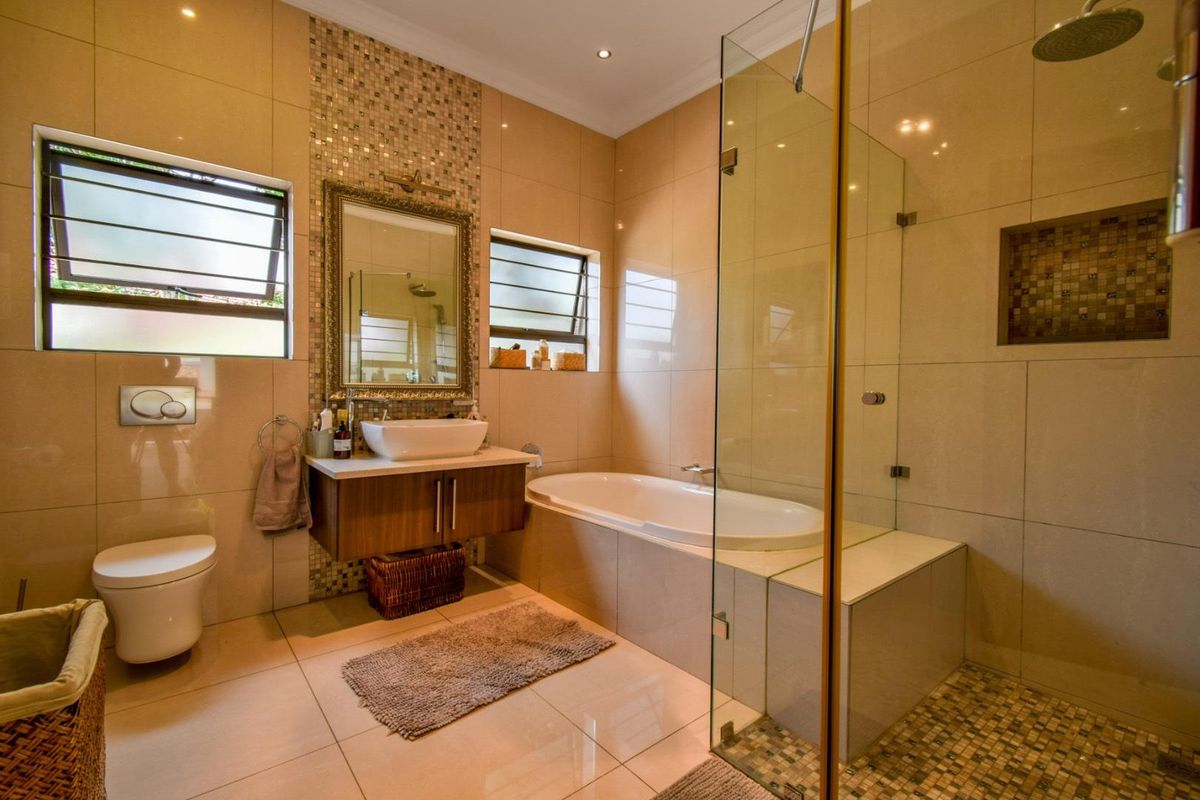 Modern bathroom featuring a floating vanity, a built-in bathtub, a glass-enclosed walk-in shower with mosaic tile accents, and large format floor tiles.