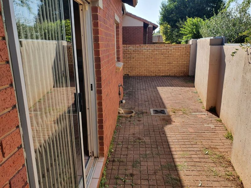 A private rear courtyard featuring brick paving and boundary walls, accessible via a sliding glass door.