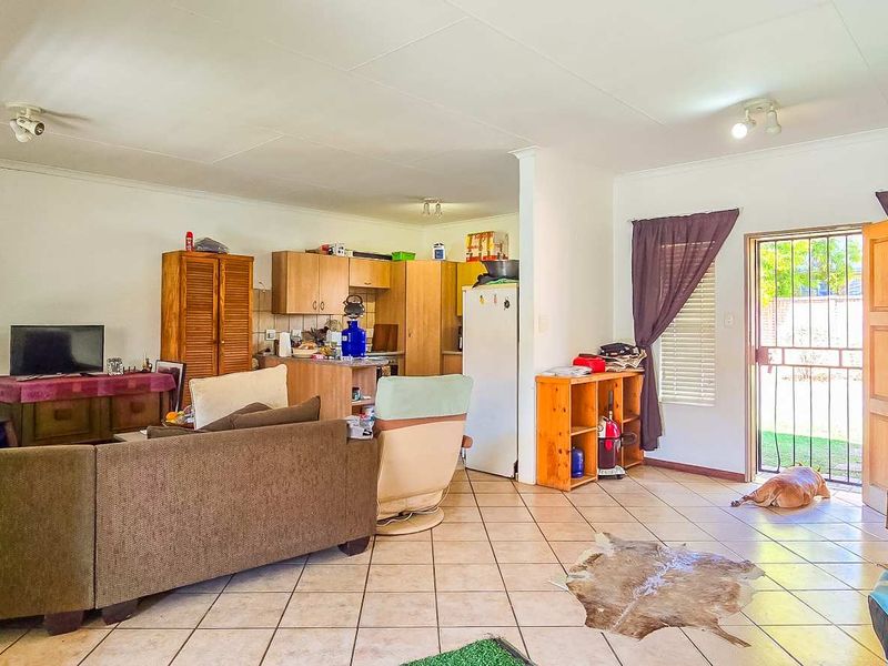 Open plan living area featuring tiled flooring and a functional kitchen space with direct access to the exterior through a security gate.