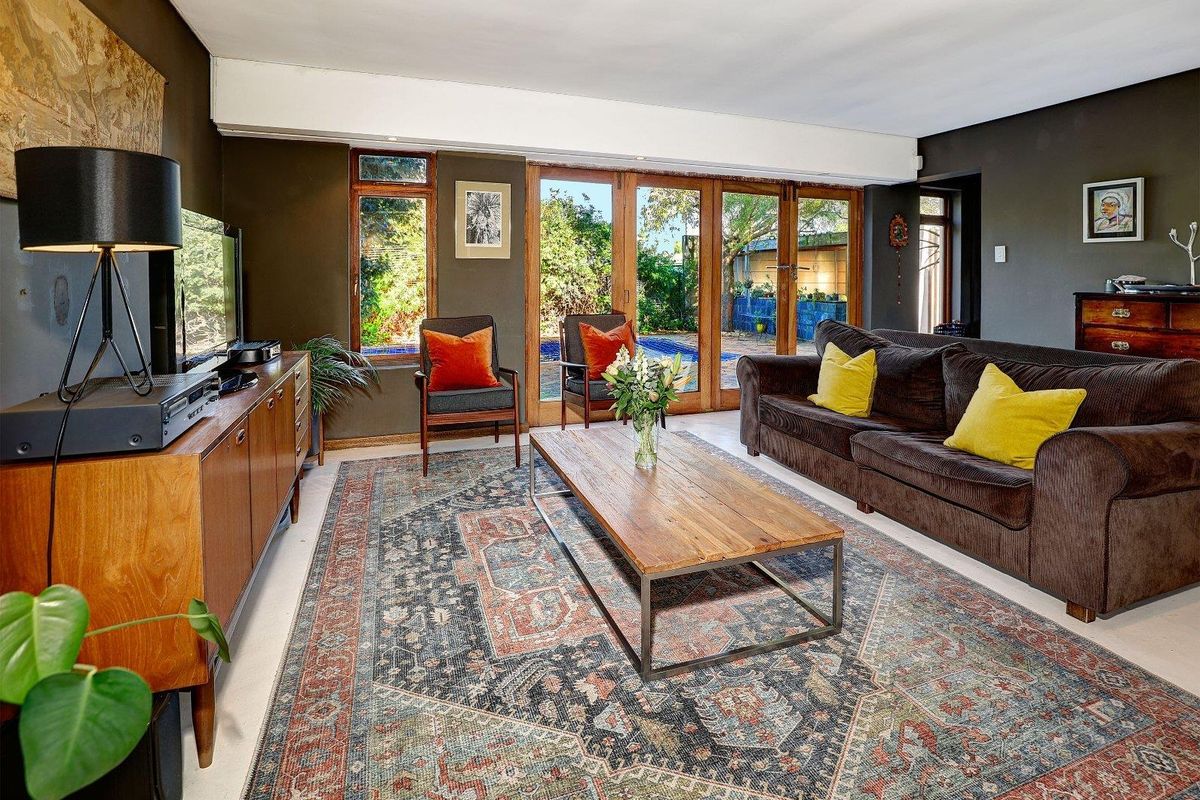 Spacious living room featuring large timber-framed glass doors that open directly to the outdoor pool area, providing excellent natural light and garden views.