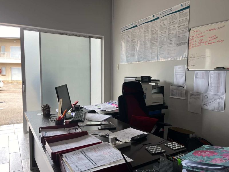 A functional office space featuring tiled flooring, a sliding glass door providing natural light, and a frosted glass partition.