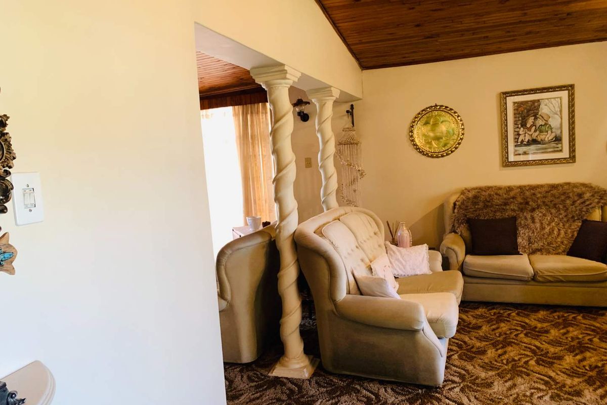 A living room featuring a timber tongue and groove ceiling and decorative spiral columns separating the space.