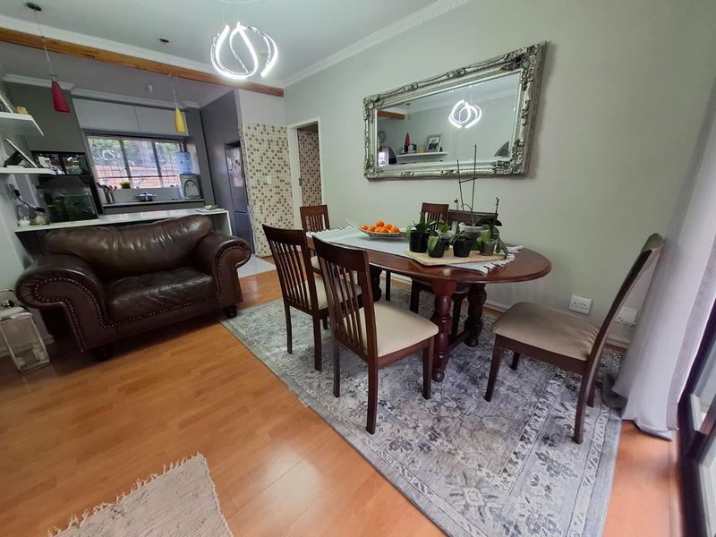 Open-plan living and dining area featuring laminate flooring, coving, and a functional kitchen space with built-in cabinetry.