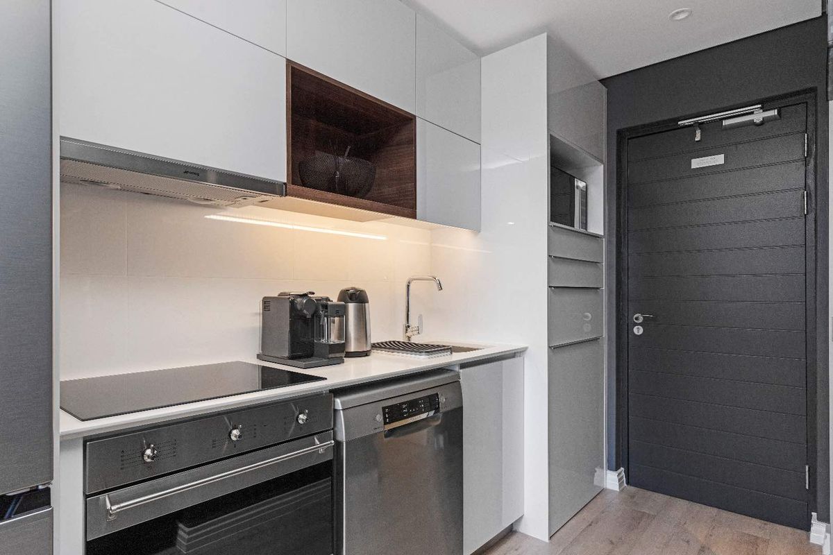 A modern, compact kitchen featuring high-gloss cabinetry, integrated appliances, a sleek electric hob, and efficient under-cabinet lighting.