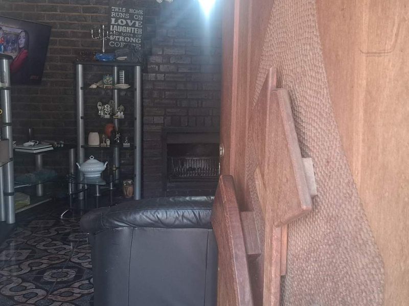 Living room area featuring an exposed brick wall and a built-in fireplace, finished with patterned floor tiles.