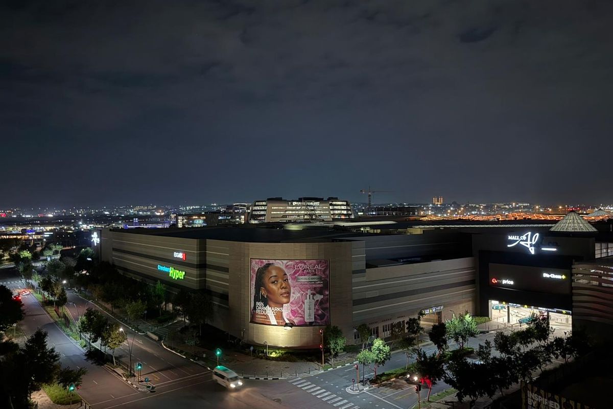 Nighttime aerial view of a large commercial shopping complex with surrounding road infrastructure and urban lighting.