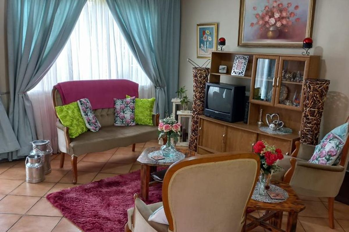 A cozy living room featuring terracotta floor tiles, large window with curtains, and neutral wall finishes, providing a comfortable and traditional living space.