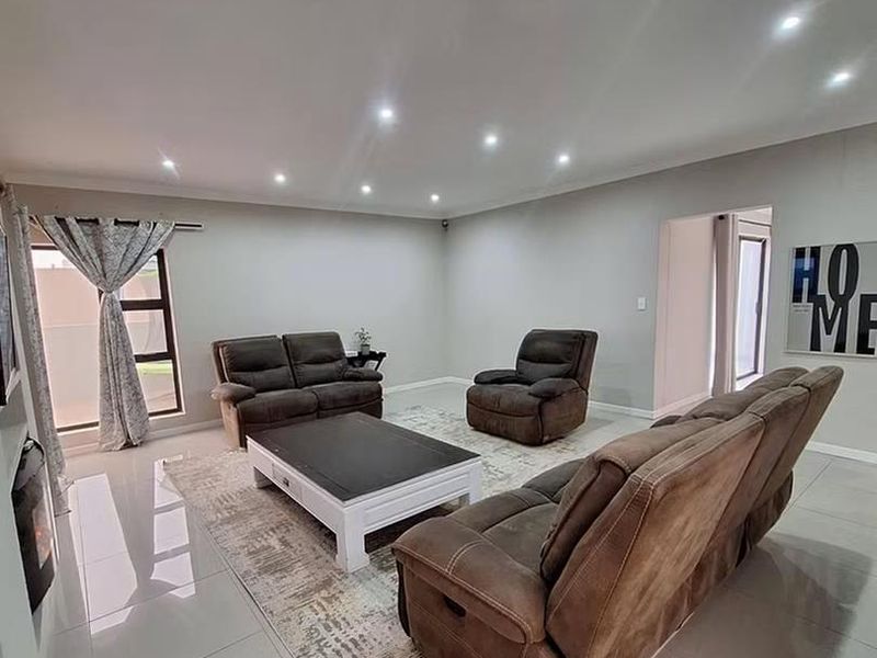 Spacious living room featuring modern tiled flooring, recessed downlighting, and a built-in fireplace, creating a bright and comfortable atmosphere.