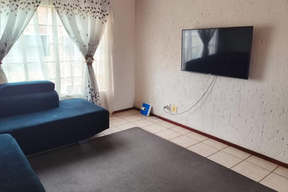 A living room featuring tiled flooring and textured wall finishes, providing a functional space for relaxation.