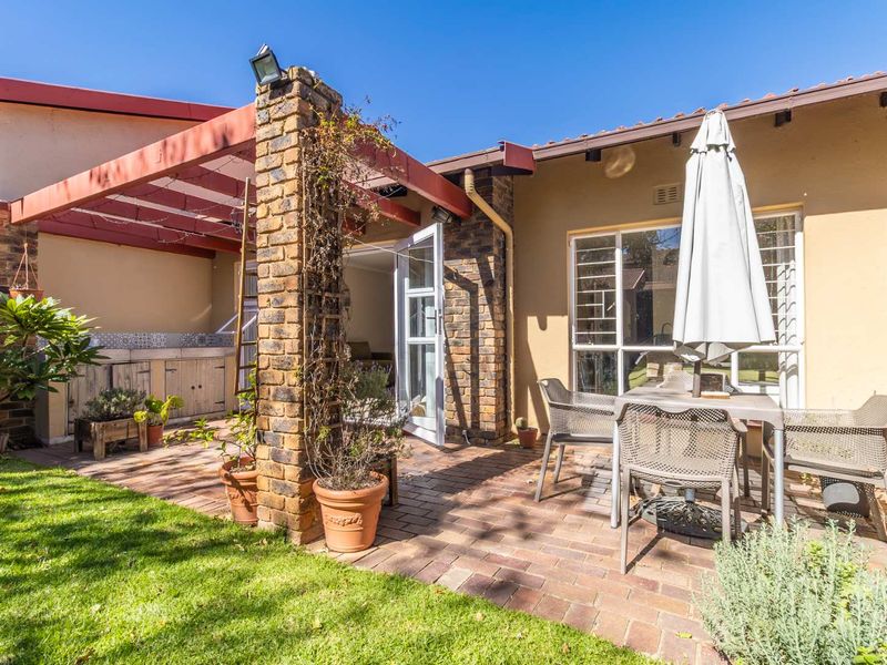 Outdoor patio area featuring a brick-paved floor, a built-in braai, and a pergola, providing a functional space for outdoor entertaining.