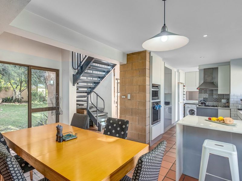 Open plan living and kitchen area featuring a central brick pillar, metal staircase, modern kitchen cabinetry, and direct access to the garden.