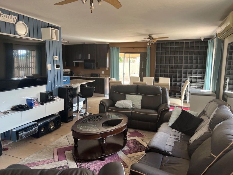 Open plan living and dining area featuring a modern kitchen with dark cabinetry, granite countertops, and direct access to the outdoor patio.