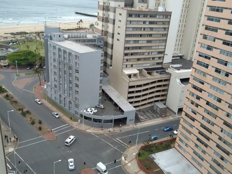 Elevated urban view overlooking a coastal street intersection and nearby high-rise apartment buildings.