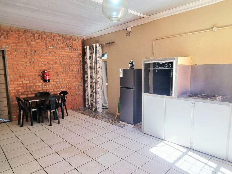 Open-plan kitchen and dining area featuring exposed brickwork, tiled flooring, and functional built-in cabinetry with integrated oven and hob.