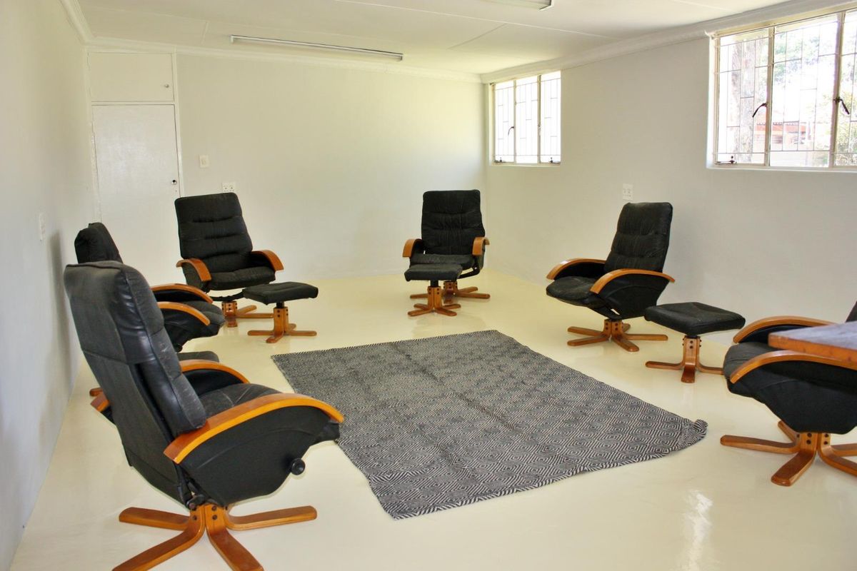 A spacious, neutral living area featuring tiled flooring, large windows with security bars, and built-in storage.