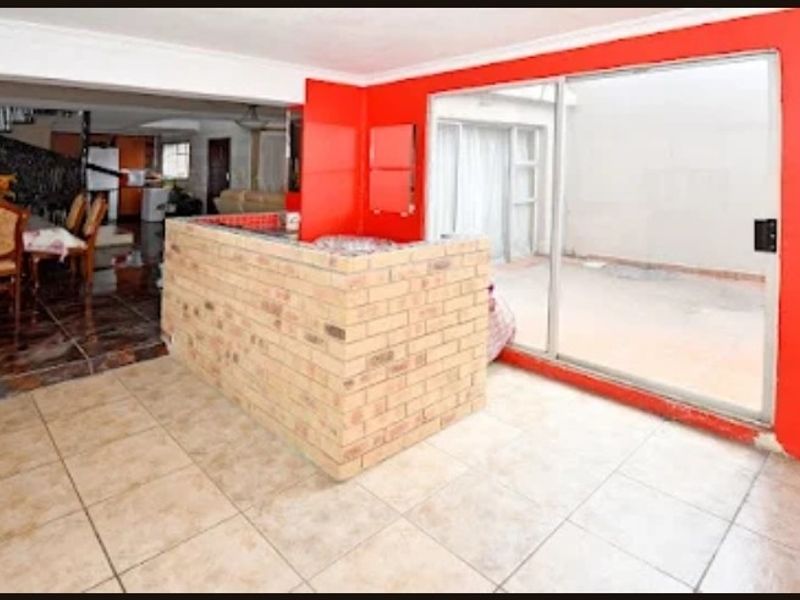 Open plan living area featuring a brick breakfast bar, tiled flooring, and sliding glass doors leading to an outdoor space.