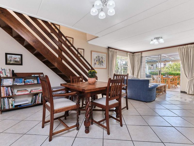 Open plan living and dining area featuring tiled flooring, a wooden staircase, and sliding glass doors leading to an outdoor patio.