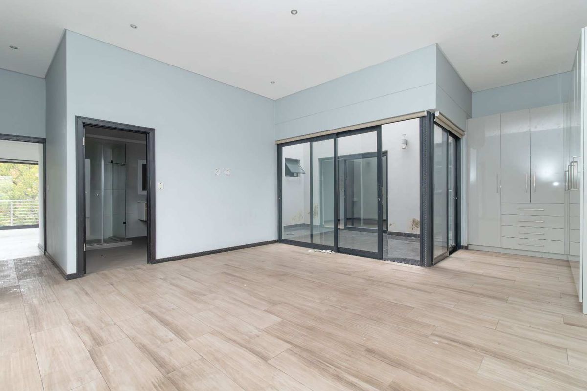 Spacious bedroom featuring light wood-look tile flooring, built-in cabinetry, and direct access to an enclosed balcony through large sliding glass doors.