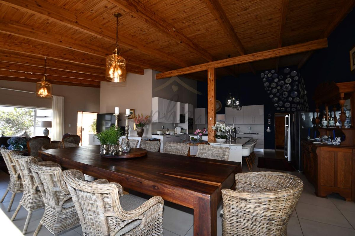 Spacious open-plan living and dining area featuring a high exposed timber beam ceiling, modern kitchen island, and neutral tiled flooring throughout.