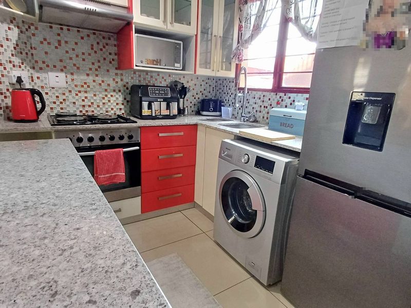 Compact kitchen featuring granite countertops, mosaic tile backsplash, built-in oven with gas hob, extractor fan, and integrated washing machine.