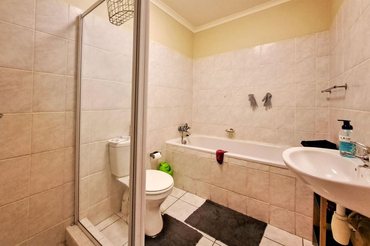 A functional bathroom featuring a built-in bathtub, a separate shower enclosure with a glass door, a toilet, and a pedestal sink.