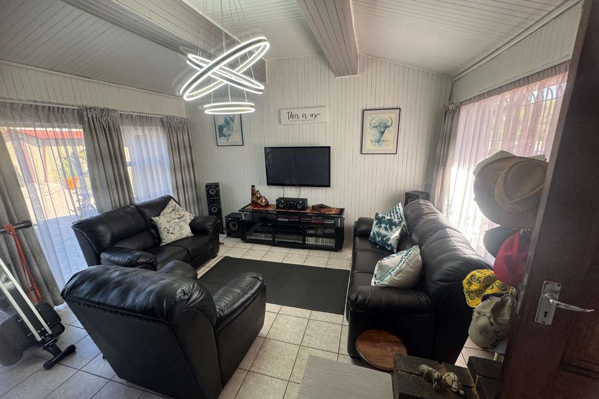 A cozy living room featuring vaulted timber-paneled ceilings, tiled flooring, and large sliding glass doors providing ample natural light.