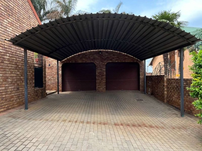 A double carport structure providing covered parking, featuring facebrick walls and paved driveway area leading to a double garage.