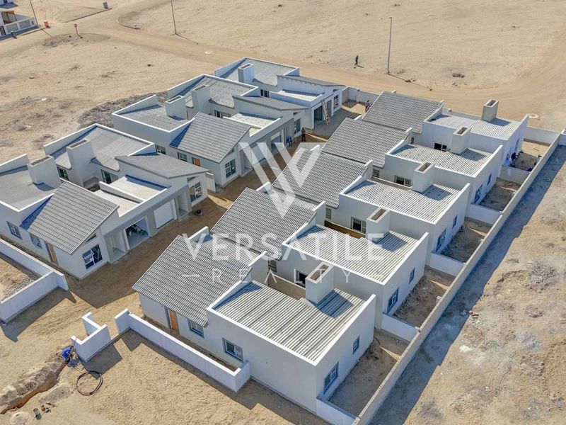 Aerial view of a modern townhouse development complex featuring multiple units with tiled roofs, boundary walls, and ongoing site development.