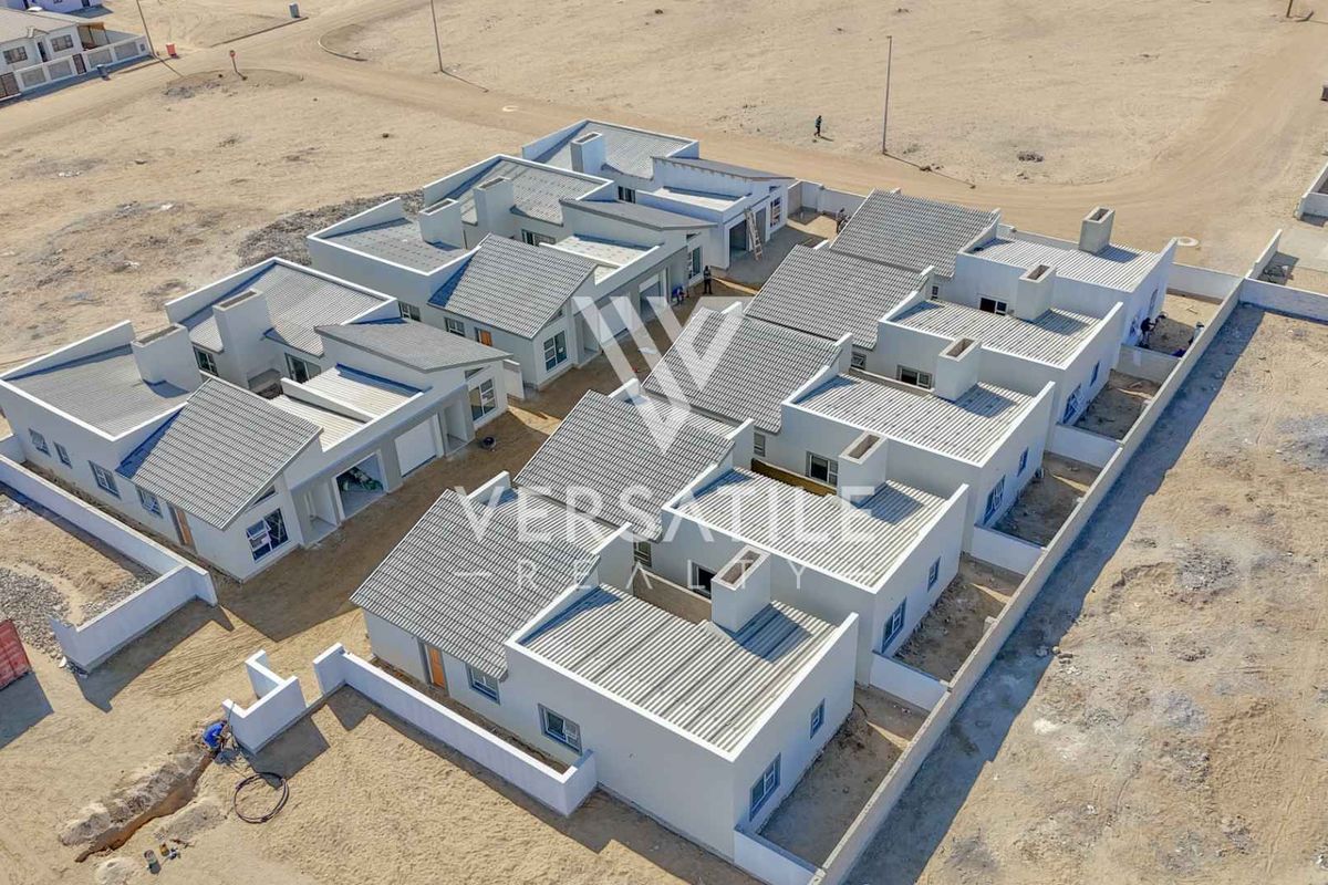 Aerial view of a modern townhouse development complex featuring multiple units with tiled roofs, boundary walls, and ongoing site development.