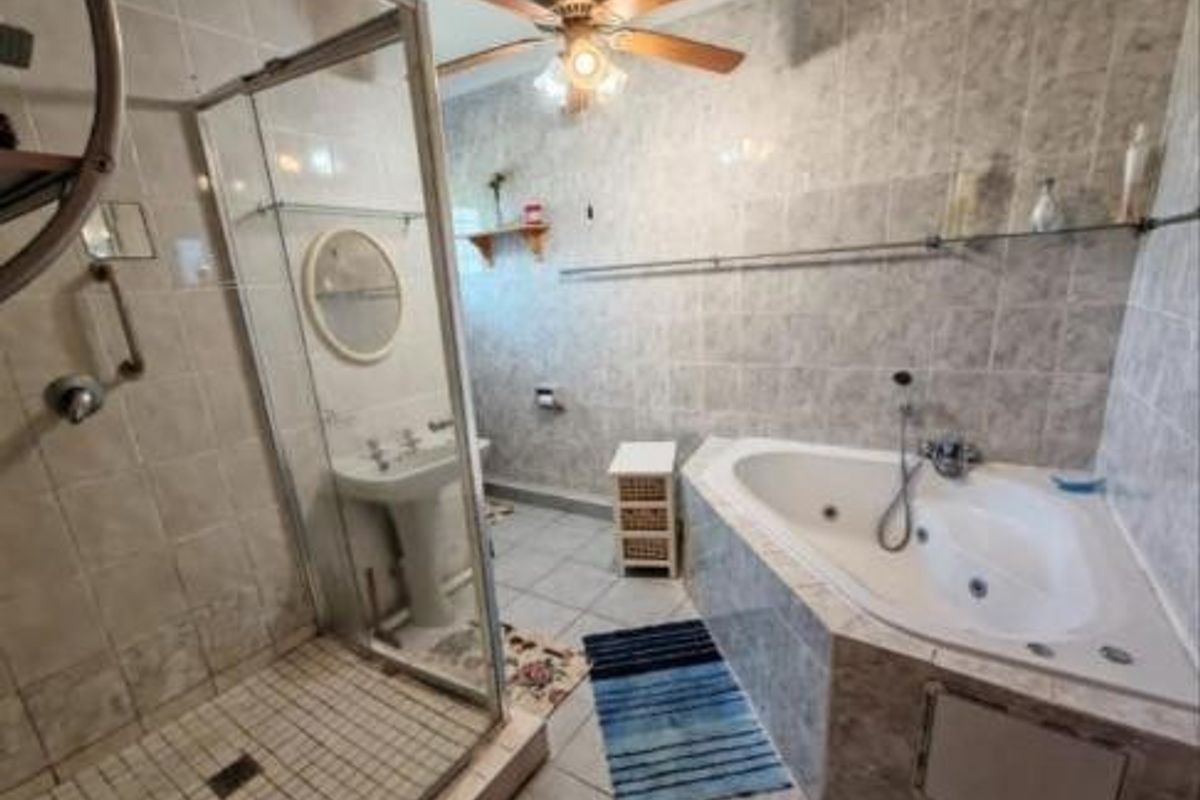 A dated bathroom featuring a corner jetted bathtub, a separate glass-enclosed shower, and a pedestal basin with full-height wall tiling.