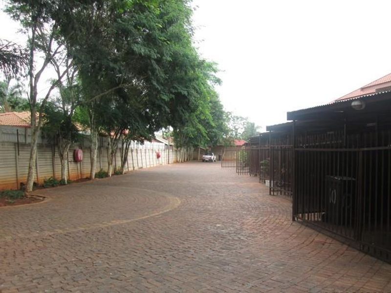 A paved driveway area within an apartment complex featuring perimeter walling and covered parking bays.