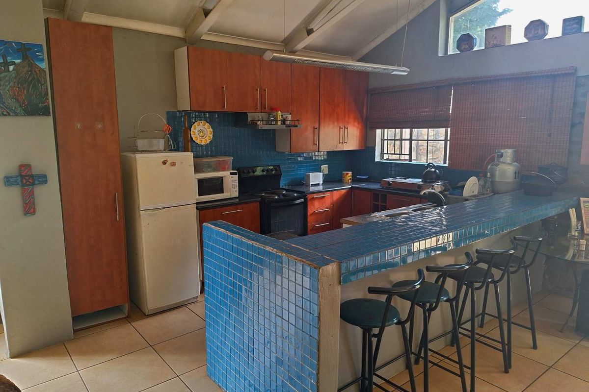 A functional kitchen featuring a tiled breakfast bar, built-in cabinetry, and exposed beam ceilings, offering a practical layout with potential for modern updates.