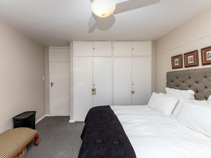 A bedroom featuring neutral walls, carpeted flooring, a ceiling fan, and ample built-in cupboard storage.