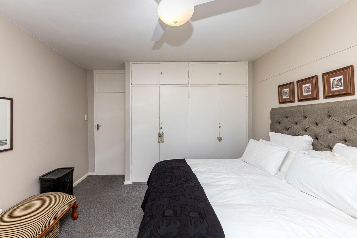 A bedroom featuring neutral walls, carpeted flooring, a ceiling fan, and ample built-in cupboard storage.
