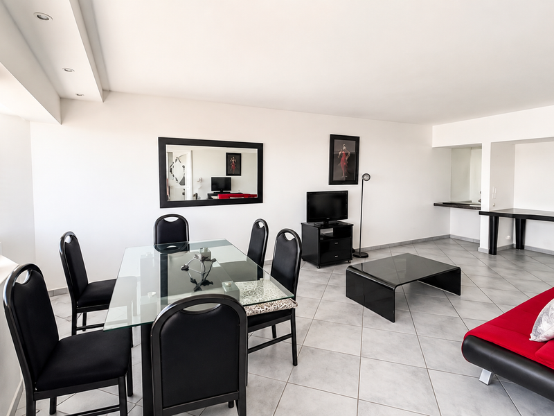 Spacious open-plan living and dining area featuring neutral ceramic floor tiles, recessed lighting, and a built-in breakfast bar counter.