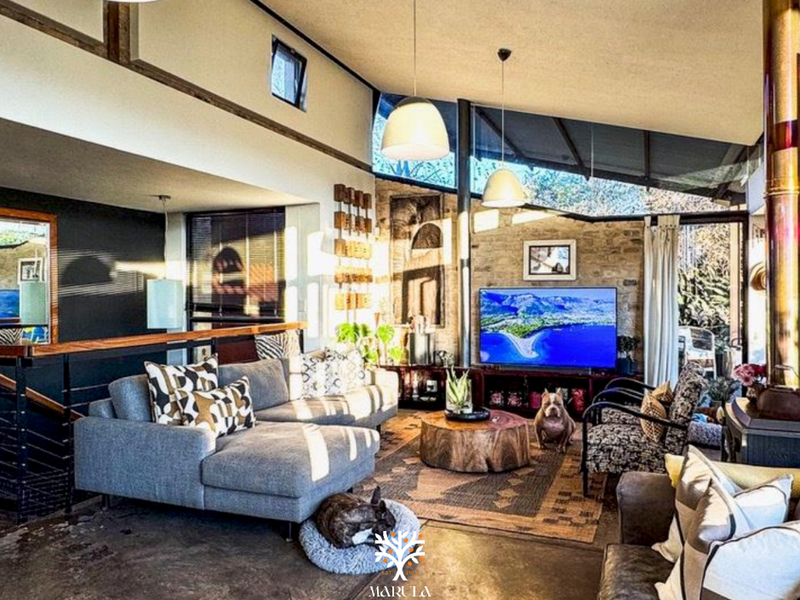 Spacious living room featuring polished concrete floors, an exposed stone feature wall, vaulted ceilings, and a wood-burning fireplace with a modern open-plan layout.
