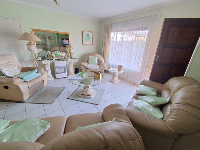 A living room featuring tiled flooring, a large window with natural light, and coved ceiling details.