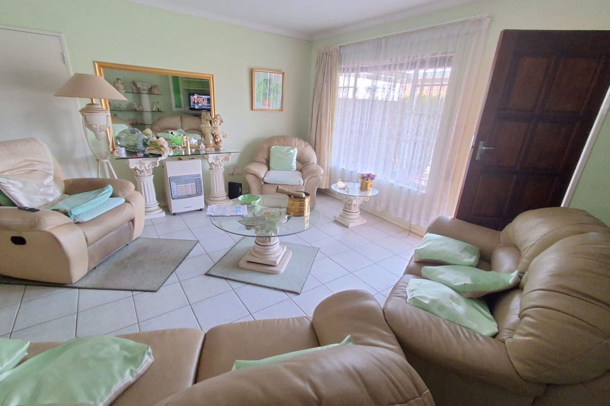 A living room featuring tiled flooring, a large window with natural light, and coved ceiling details.