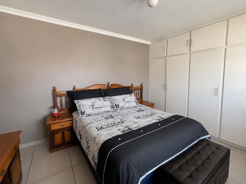A bedroom featuring tiled flooring, neutral wall paint, and extensive built-in cupboard storage.