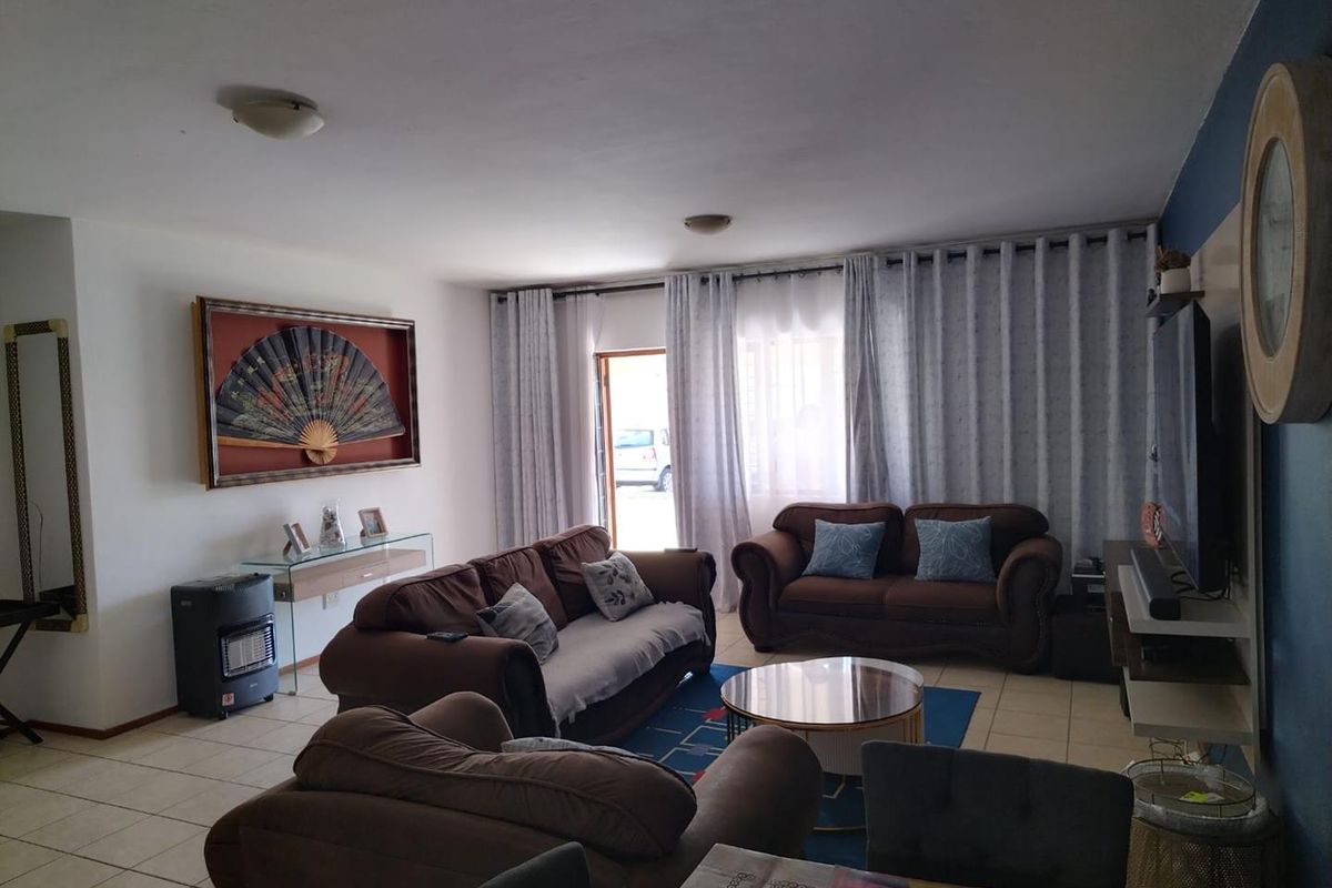 A comfortable living room featuring tiled flooring and a sliding glass door that provides access to the exterior.
