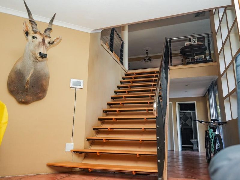 Entrance hall featuring a central open-tread staircase with metal balustrades and tiled flooring, leading to an upper level landing.