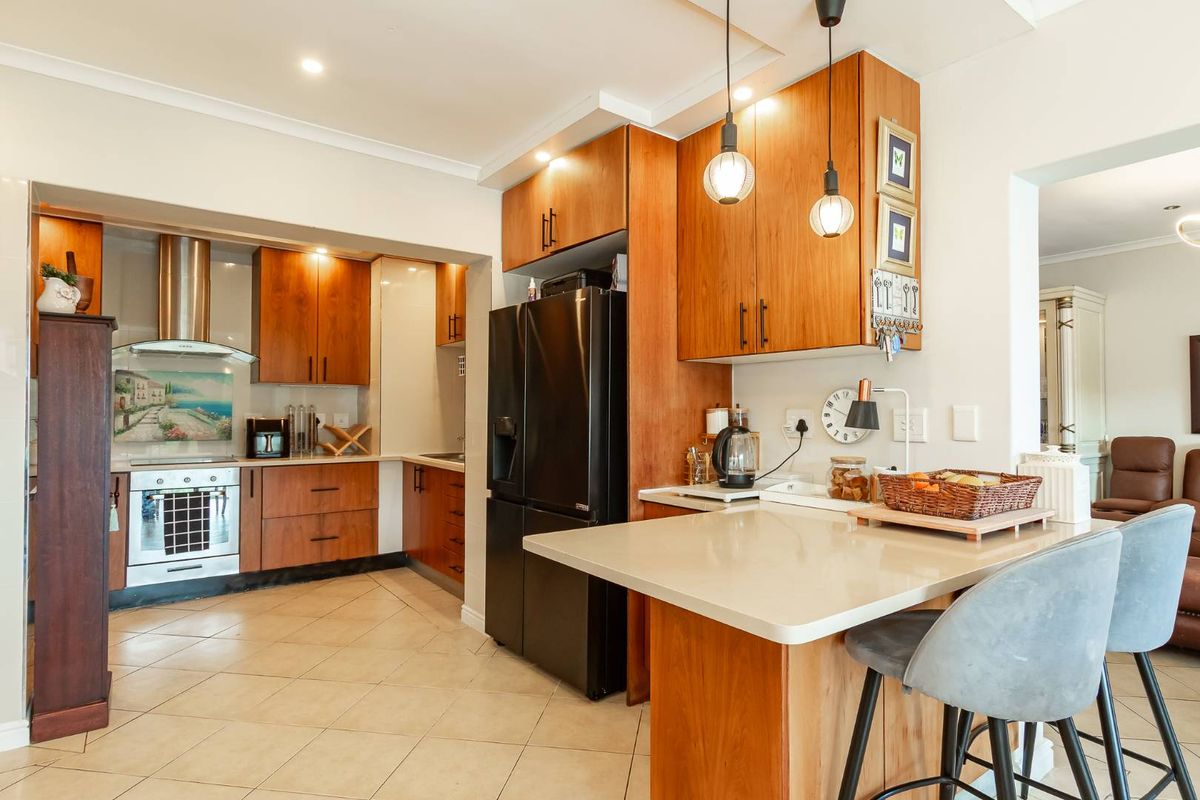 A well-maintained kitchen featuring warm wood cabinetry, stone countertops, integrated appliances, and a breakfast bar, creating a functional and inviting culinary space.